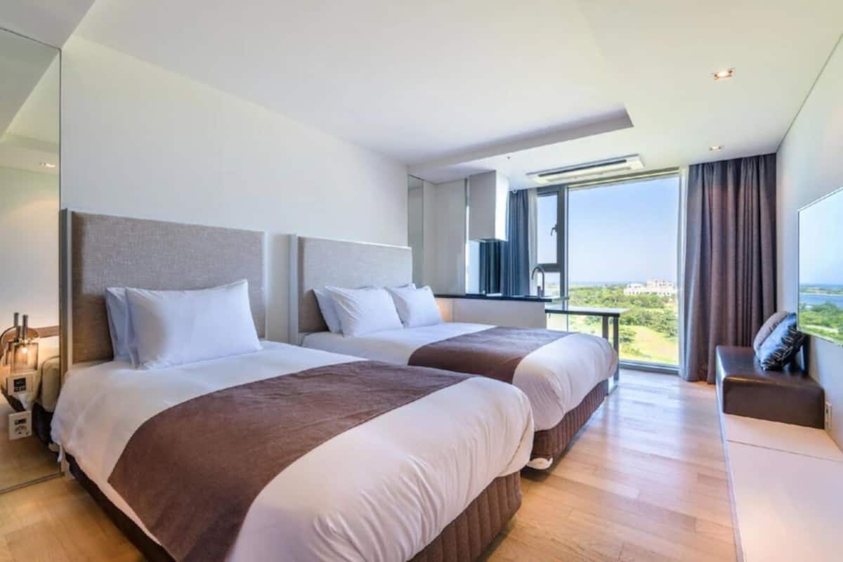 Ein modernes Hotelzimmer mit zwei Betten, einem Balkon mit Stadtblick und einem großen Fenster.