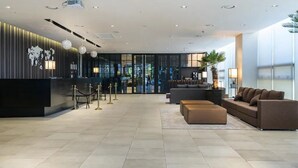 En moderne lobby med receptionsdisk, siddeområde og stort vindue.