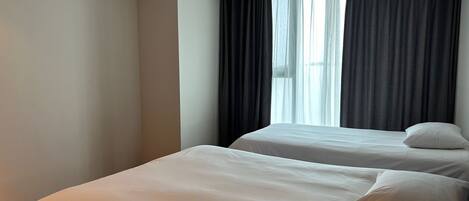 A hotel room with two beds, a large window with curtains, and an air conditioning unit on the ceiling.