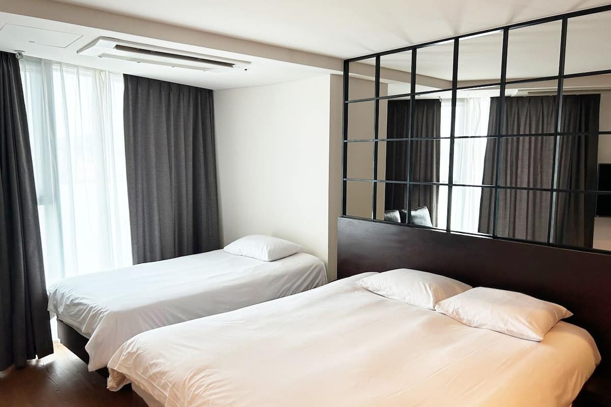 Ein Hotelzimmer mit zwei Betten, einem großen Spiegel und einem Fenster mit Vorhängen.
