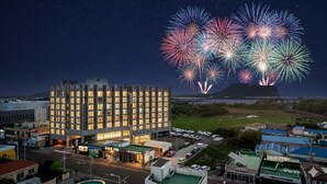 Et hotel med moderne design, der viser en stor bygning med flere etager og en parkeringsplads foran.