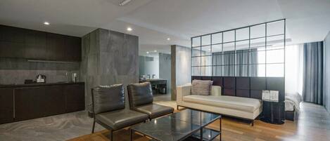 Una sala de estar moderna con un sofá, dos sillones, una mesa de centro y un ventanal con cortinas.