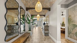 A hallway with a stone floor, large mirrors, and a hanging light fixture. - The Luxe Palmilla | Private Pool and Spa, Custom-Themed Kids Bedrooms (Kissimmee)