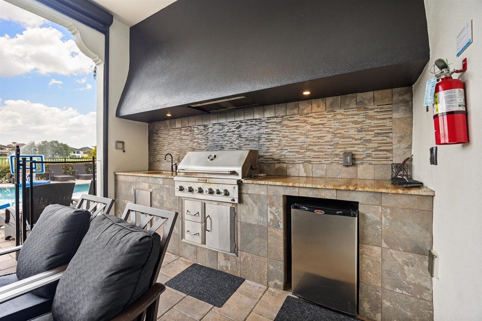 An outdoor kitchen with a grill, a dishwasher, and a fire extinguisher.