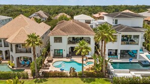 A residential area with multiple houses, a central swimming pool, and surrounding greenery. - The Luxe Palmilla | Private Pool and Spa, Custom-Themed Kids Bedrooms (Kissimmee)