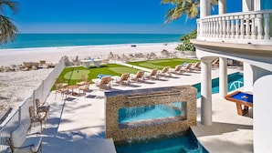 A pool area with lounge chairs and a water feature. - Anna Maria Grand: Gulf Front! On the Beach! Sleeps 22 by Anna Maria Life Vacation Rentals (Bradenton Beach)