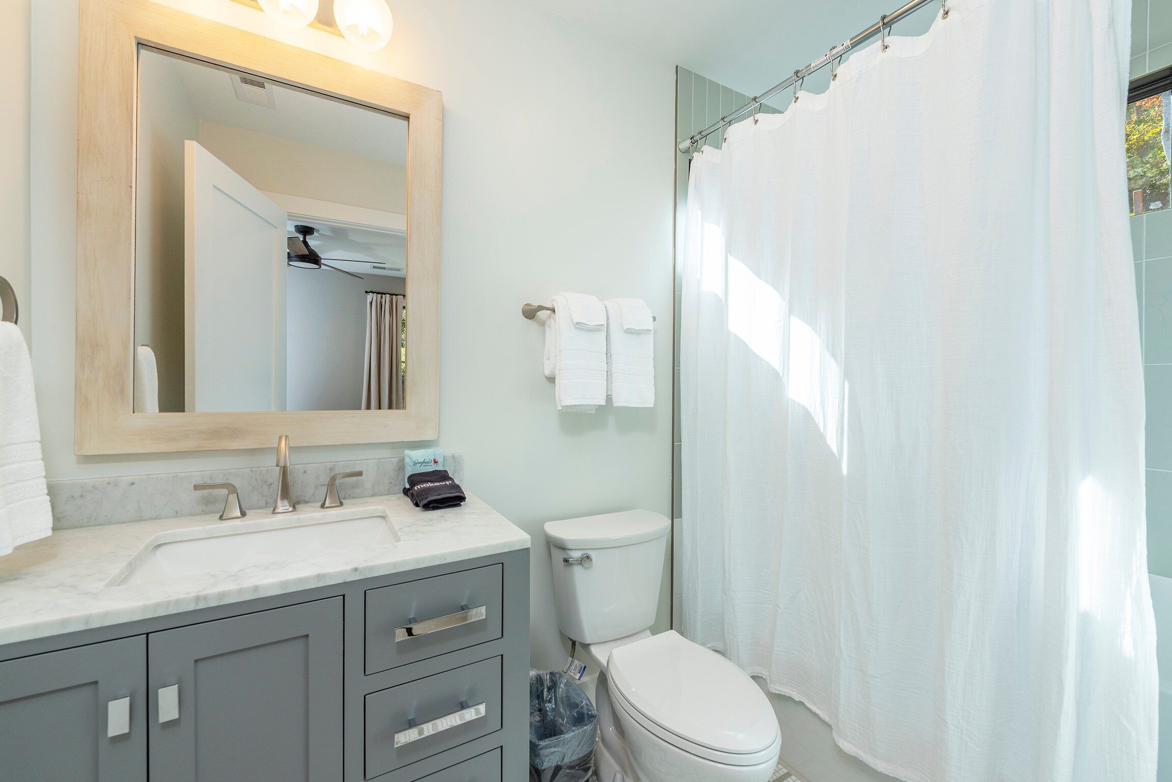 Un baño con lavamanos blanco, un espejo, inodoro y cortina de ducha.