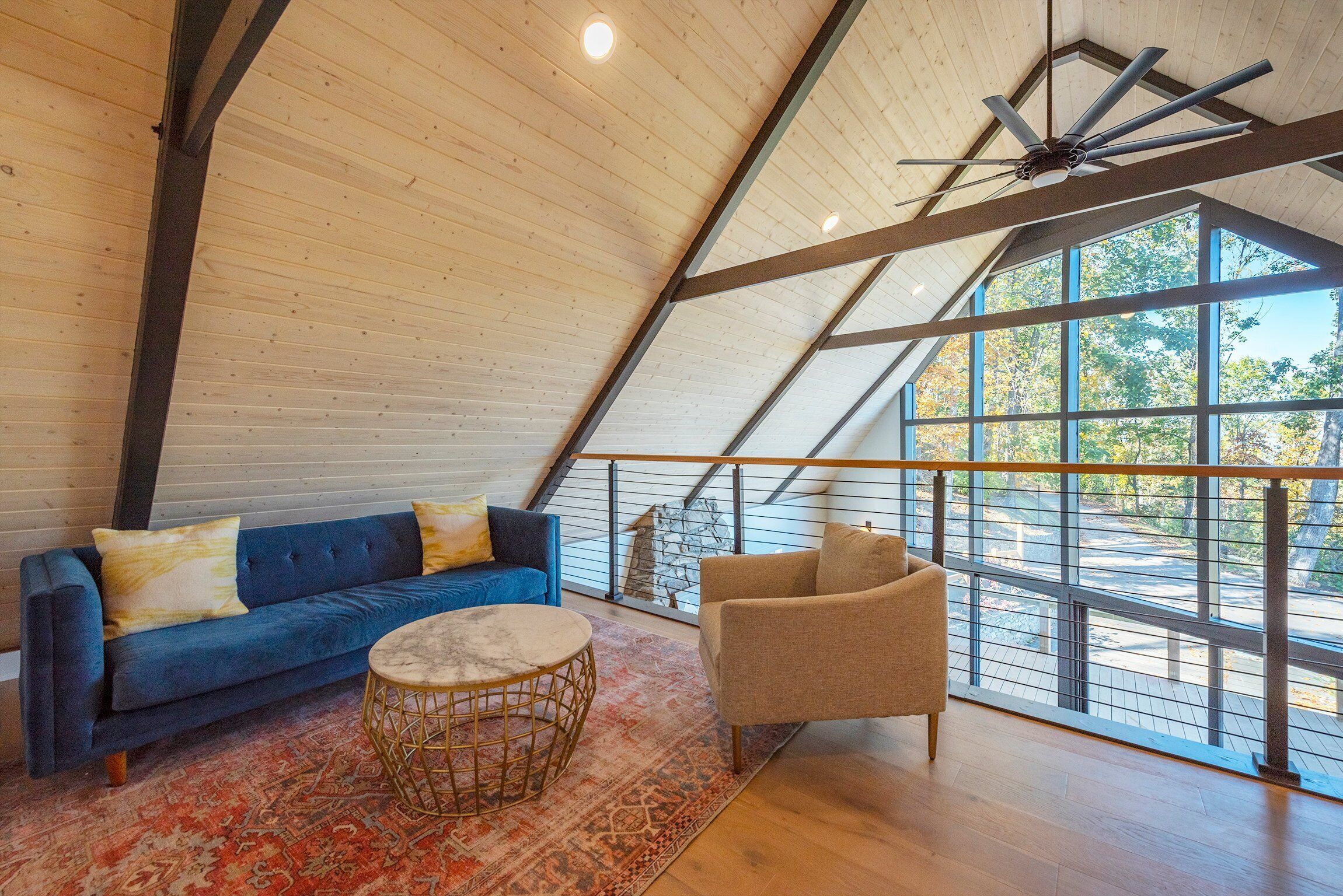 A spacious loft with a high ceiling, a blue sofa, a beige armchair, and a round coffee table.