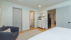 Une chambre à coucher comprenant un lit, une commode, un miroir et une porte donnant sur une salle de bain.