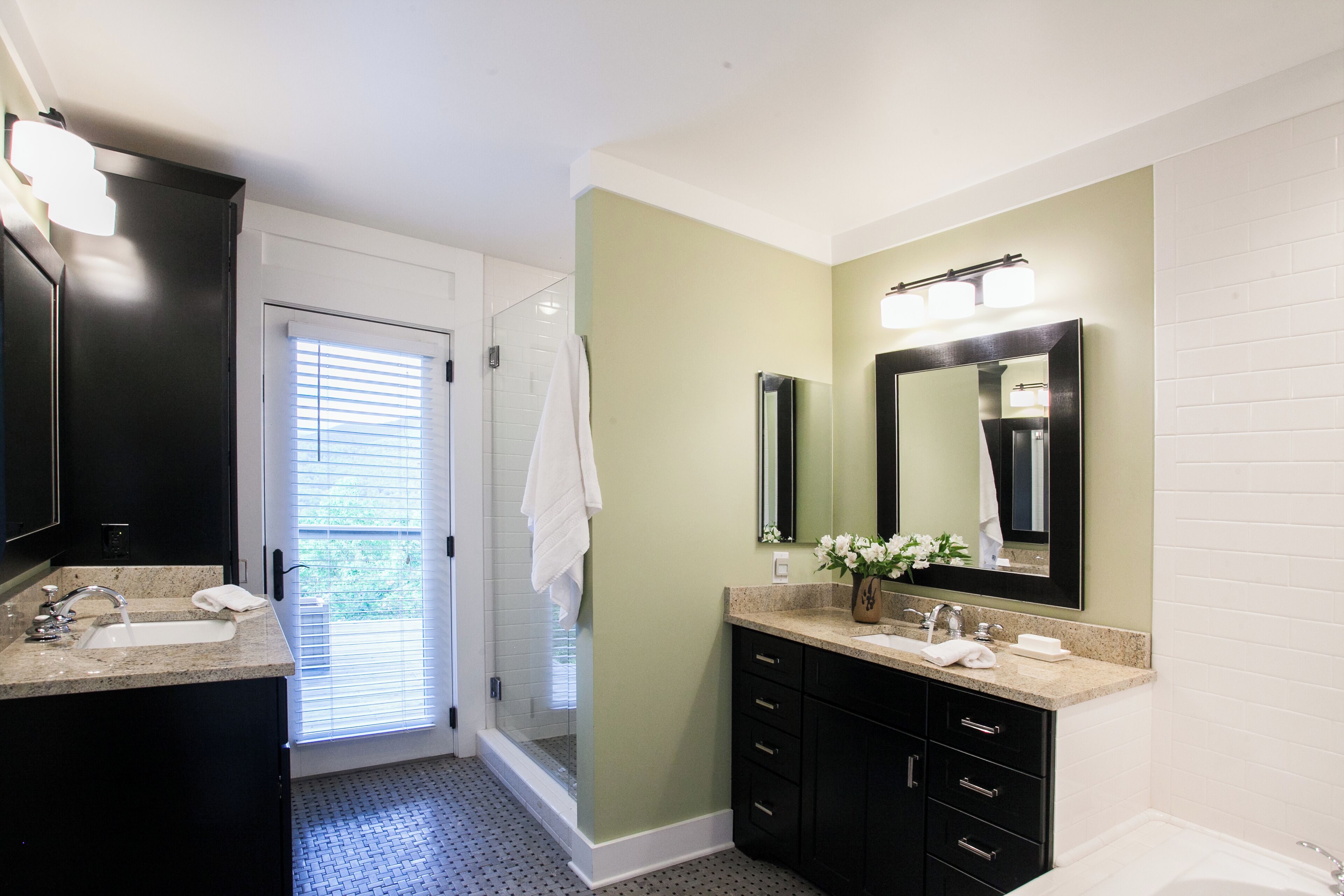 A bathroom with a double sink, a large mirror, and a shower area.