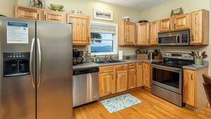 A kitchen with wooden cabinets, stainless steel appliances, a dishwasher, a microwave, and an oven. - Ridgetop Hideaway | Pet-friendly, Hot Tub, Fire Pit & Mountain Views! (Swannanoa)