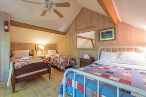 Una habitación acogedora con dos camas de madera, un ventilador de techo y techo de madera.