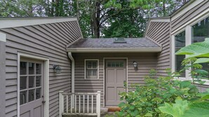A small, single-story house with a front door, a small porch, and a window. - Little Piney | Pet Friendly & Golf Course Views! (Black Mountain)