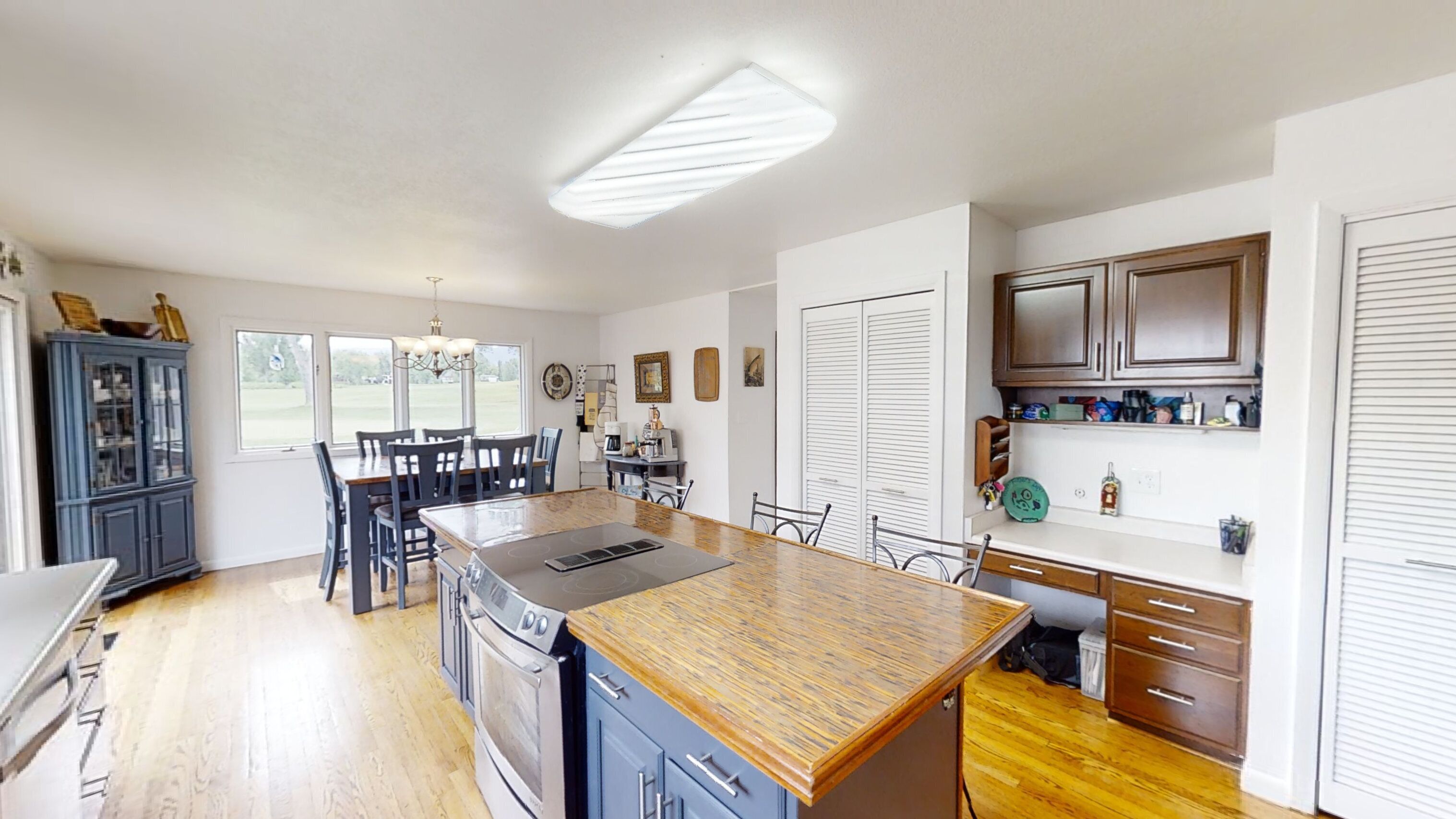 A kitchen with a central island, wooden cabinets, and a dining area with chairs.
