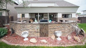 A modern house with a stone exterior, a covered patio, and a barbecue area. - Delightful 6 bedroom house on Paradise Valley Country club golf course (Casper)