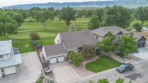 A residential area with houses, a driveway, a lawn, and a golf course in the background. - Delightful 6 bedroom house on Paradise Valley Country club golf course (Casper)