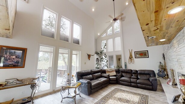 A spacious living room with a large leather sofa, a wooden ceiling, and multiple windows. - Delightful 6 bedroom house on Paradise Valley Country club golf course (Casper)
