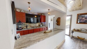 A kitchen with red cabinets, a large black TV, and two pendant lights. - Delightful 6 bedroom house on Paradise Valley Country club golf course (Casper)