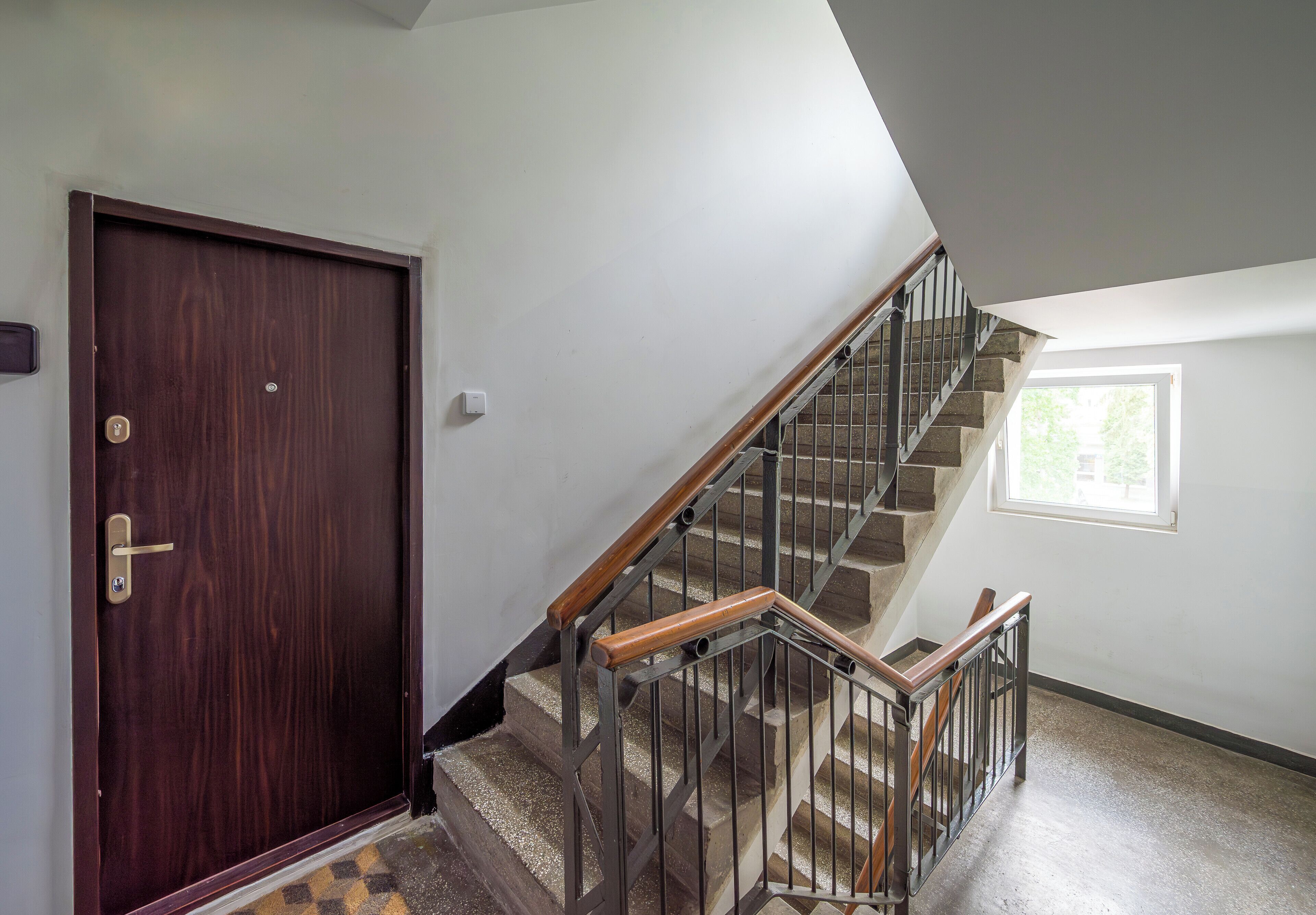 A staircase with a wooden handrail and metal balusters, leading to an upper floor.
