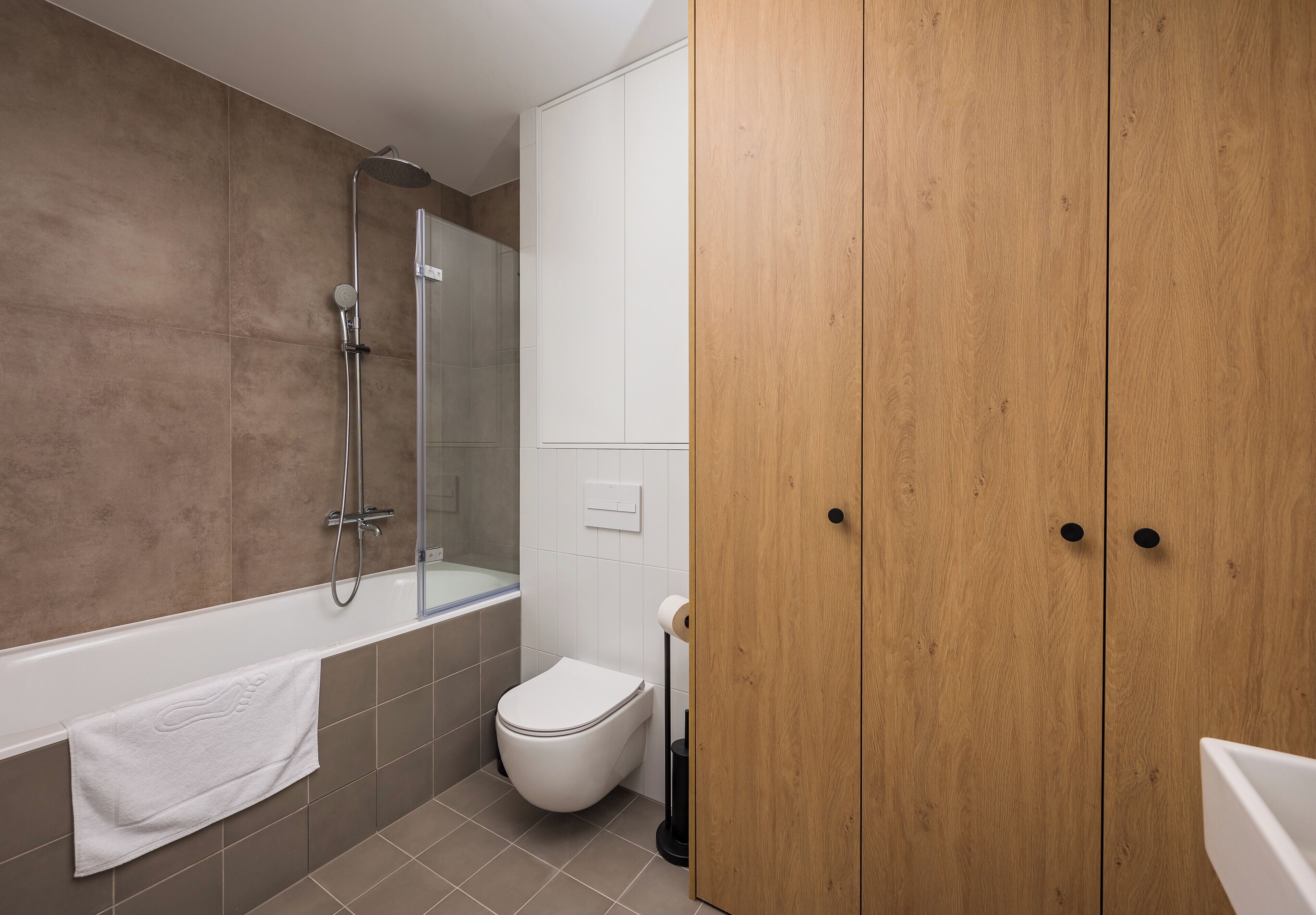 Une salle de bain moderne avec une baignoire, des toilettes et une armoire en bois.