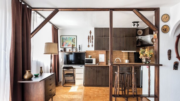 Una cocina moderna con armarios de madera, microondas y una zona de comedor con taburetes.