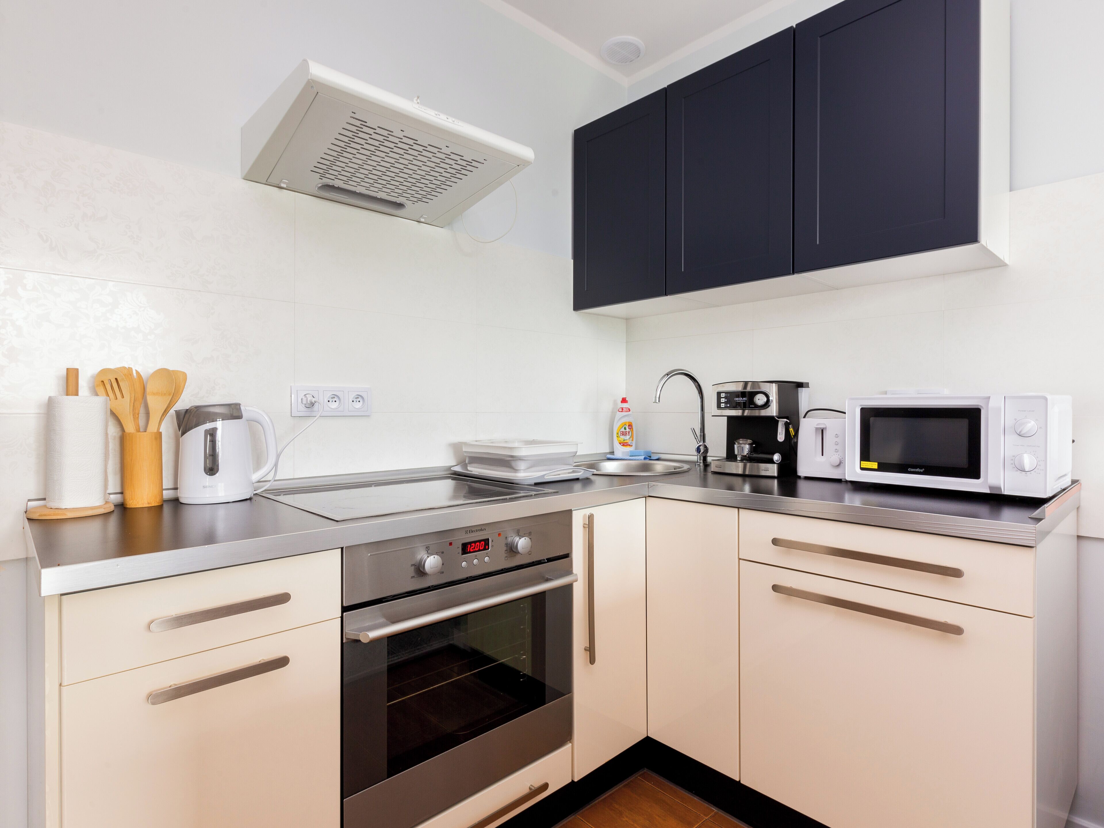 A modern kitchen with stainless steel appliances, wooden utensils, and a coffee maker.