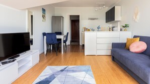 Una sala de estar moderna con un televisor de pantalla plana, un sofá y un comedor con mesa y sillas.