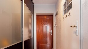 Un pasillo con una puerta de madera, un interruptor de luz en la pared y una pared con textura.