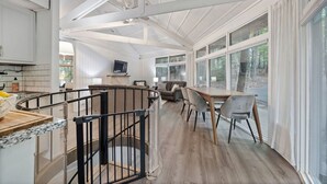 Un hivernacle ampli amb sostre alt, finestres grans, zona de dinar i cuina amb televisió.