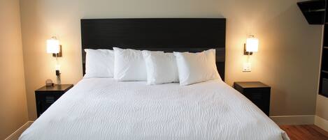 A neatly made bed with white linens and a dark headboard, flanked by two bedside tables with lamps.