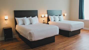 Habitación de hotel con dos camas, suelo de madera y lámparas de noche.