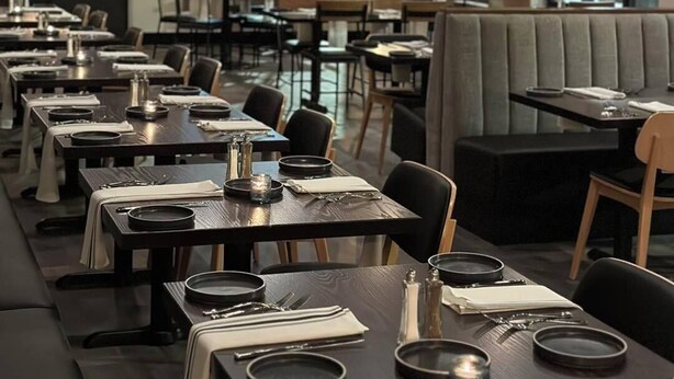 A restaurant with multiple tables and booths, large windows, and a modern interior design. - The Principal Hotel (Columbia)