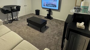 A living room with a TV, a coffee table, a couch, a small table with a keyboard, and a refrigerator. - Entire Guest Suite/Separate Entrance/Free Parking in Winnipeg (Winnipeg)