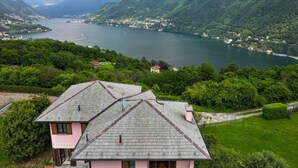 Uma casa com telhado inclinado, rodeada por vegetação exuberante e um lago.