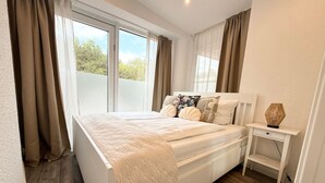 Un dormitorio con cama, mesita de noche y vistas al exterior.