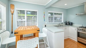 Una cocina compacta con armarios blancos, una mesa de madera y una estufa.