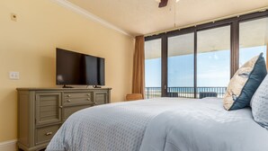 Un dormitorio con cama, cómoda, televisión y balcón con vistas.