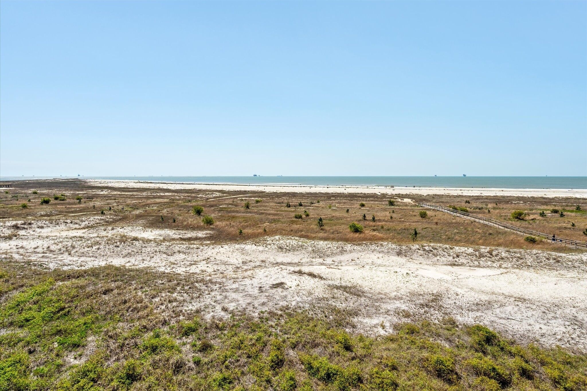 A coastal landscape with sparse vegetation and a distant beach.