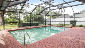 A covered swimming pool with a brick floor and metal railings.