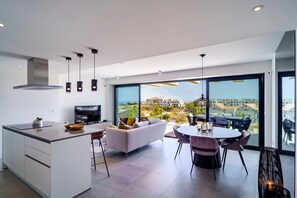 A modern kitchen with a large island, a dining area with a round table and chairs, and a sofa.