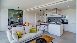 A modern living room with a sofa, coffee table, and a kitchen area with bar stools. - Apartment 'Oasis 325' with Sea View, Wi-Fi and Air Conditioning (Estepona)