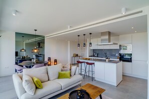 A modern living room with a sofa, coffee table, and a kitchen area with bar stools.
