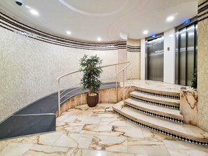 A marble staircase leading to an elevator, surrounded by tiled walls and a potted plant. - Apartment 'Ametlla Mar Benidorm' with Sea View, Shared Pool and Wi-Fi (Benidorm)