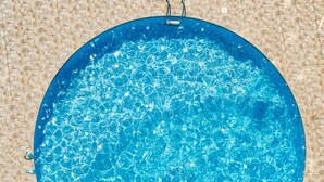 Une piscine circulaire à l’eau claire, entourée d’une terrasse carrelée.