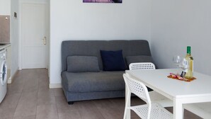 Ein modernes Wohnzimmer mit einem grauen Sofa, einem weißen Tisch und einem Sonnenuntergangsbild.