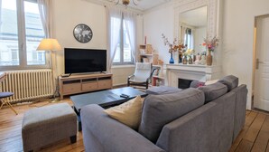 A living room with a sofa, television, and a fireplace. - Miraflores – Spacious, Elegant Apartment in Central Périgueux with Wi-Fi (Périgueux)