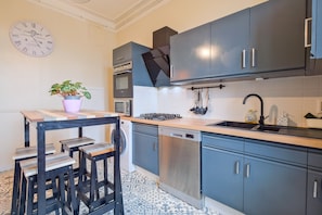 A kitchen with grey cabinets, a stainless steel dishwasher, a gas stove, and a sink.