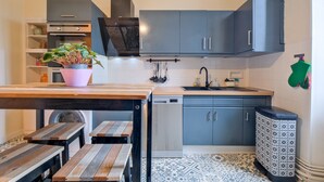 A compact kitchen with grey cabinets, a built-in oven, a sink, and a patterned floor. - Miraflores – Spacious, Elegant Apartment in Central Périgueux with Wi-Fi (Périgueux)