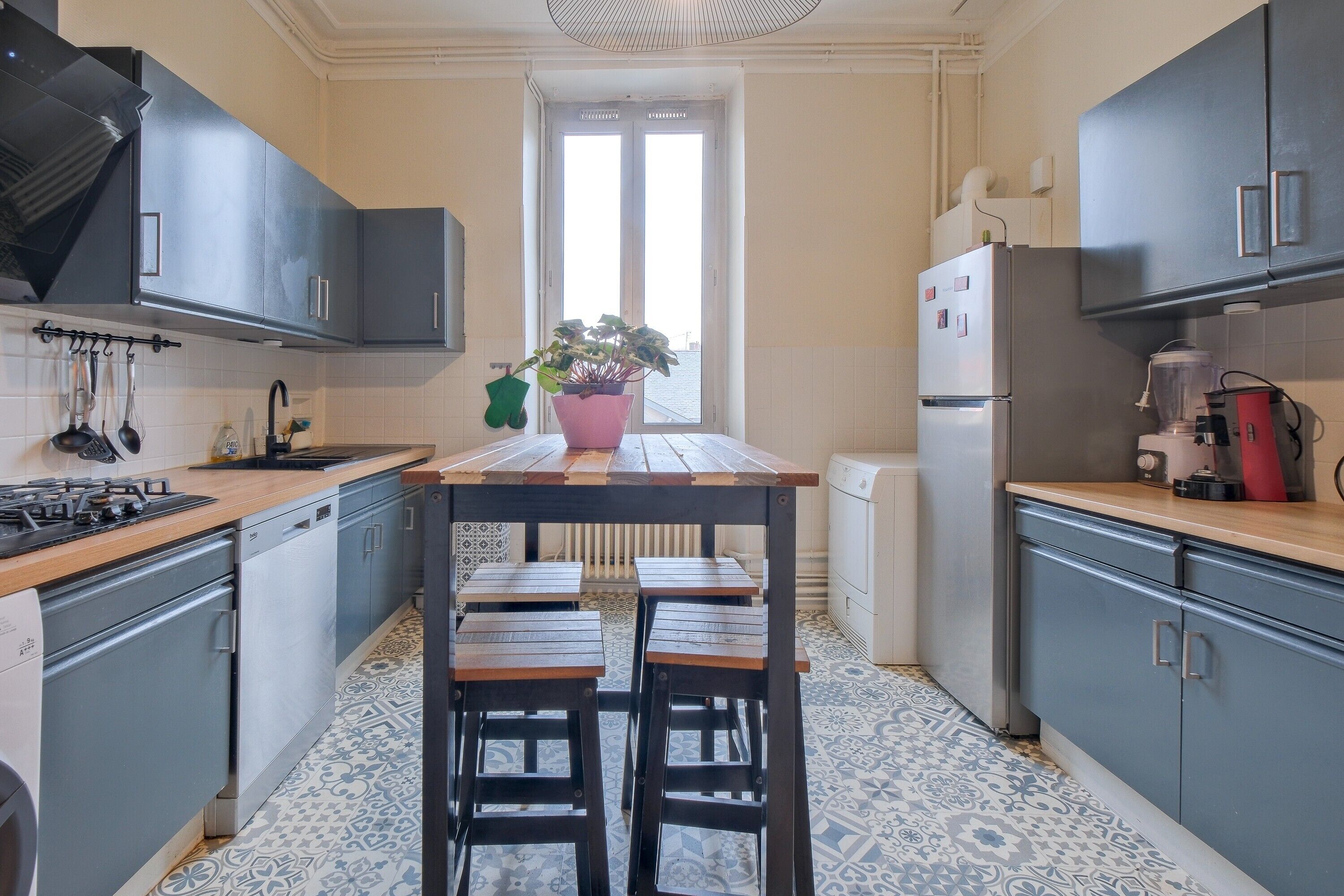 Une cuisine de taille réduite avec un îlot central, une fenêtre et un radiateur.