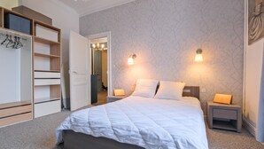 A bedroom with a bed, bedside tables, a wardrobe, and a mirror. - Miraflores – Spacious, Elegant Apartment in Central Périgueux with Wi-Fi (Périgueux)